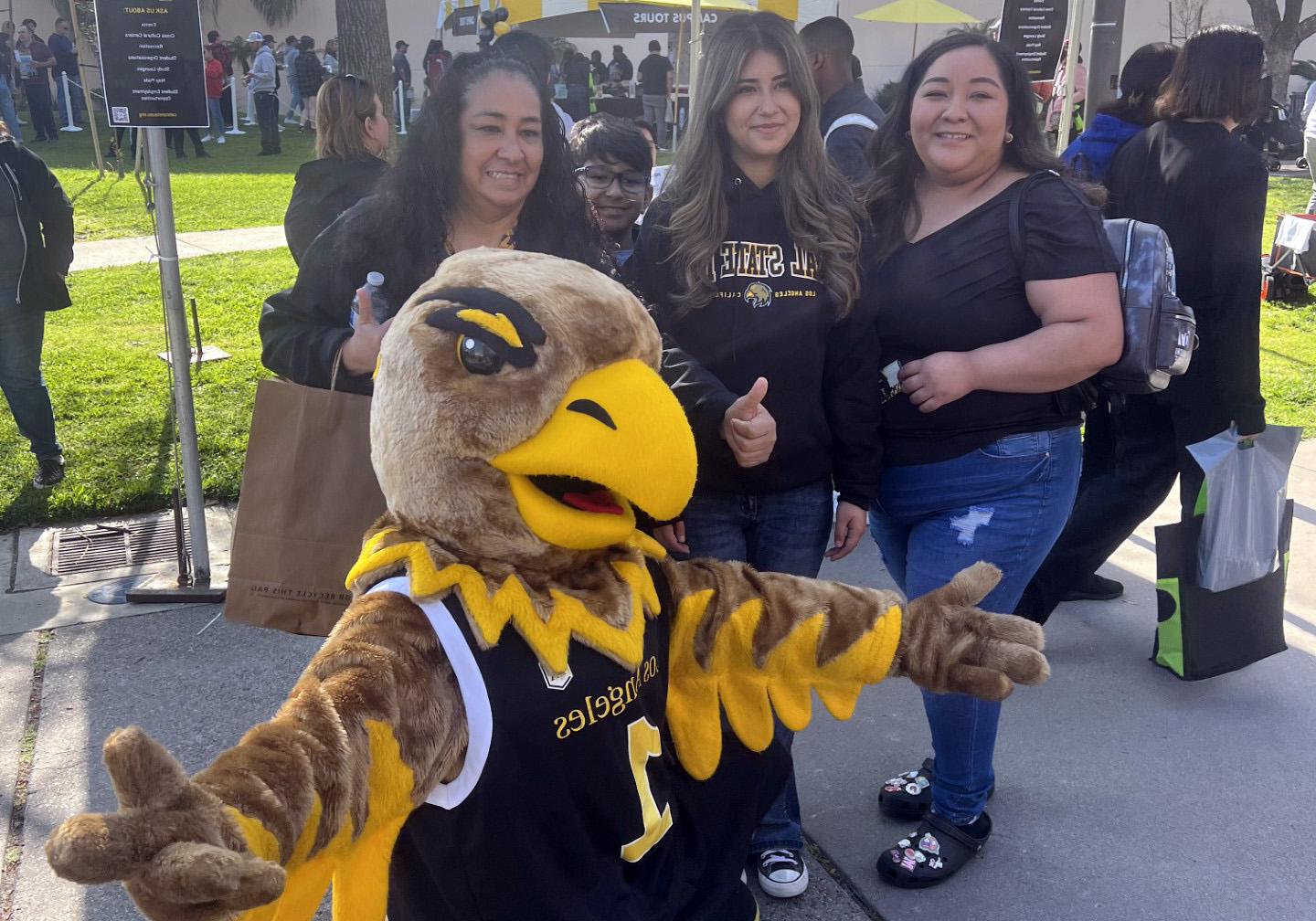 Eddie the Golden Eagle spreads arms open while posing with students.