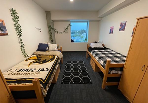 dorm room with two beds, desks and dressers.