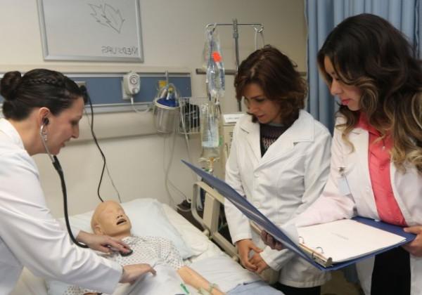 Master's students inspect a dummy patient in the Simulation Lab.
