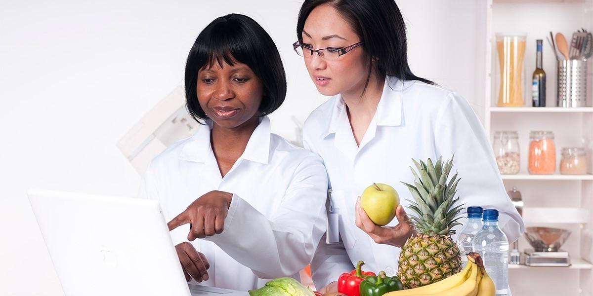 两位女性营养学家在笔记本电脑上看实验结果.