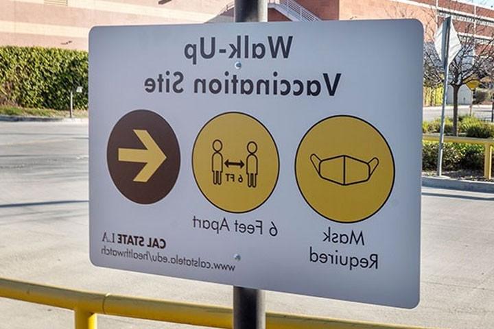 Walk-up Vaccination Site sign advises visitors to wear masks and stay 6 feet apart