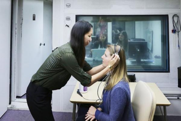 听力学学生在实验室给她的病人戴耳机. 