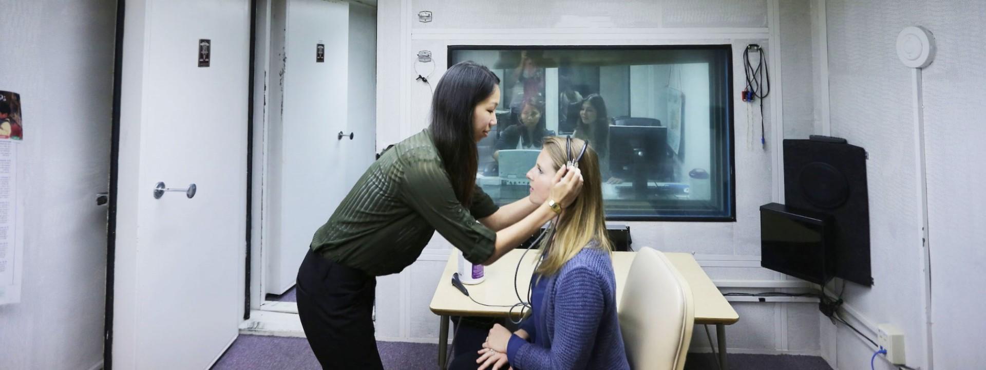听力学学生在实验室给她的病人戴耳机. 