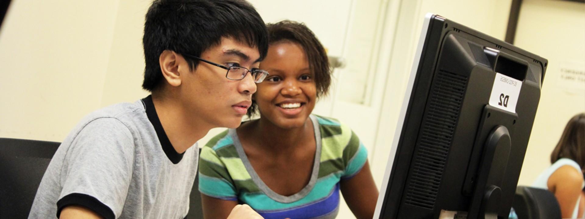 两个荣誉学院的学生聚精会神地面对着电脑屏幕. 